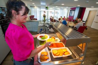 Service-Mitarbeiterin Astrid Nötzold portioniert das Essen, das frisch aus dem Regenerier-Ofen kommt. Foto: SMMP/Ulrich Bock